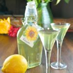 Homemade limoncello recipe in a clear jar and liquor glasses