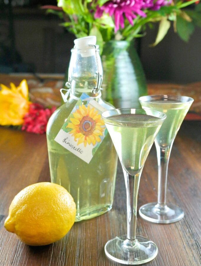 Homemade limoncello recipe in a clear jar and liquor glasses