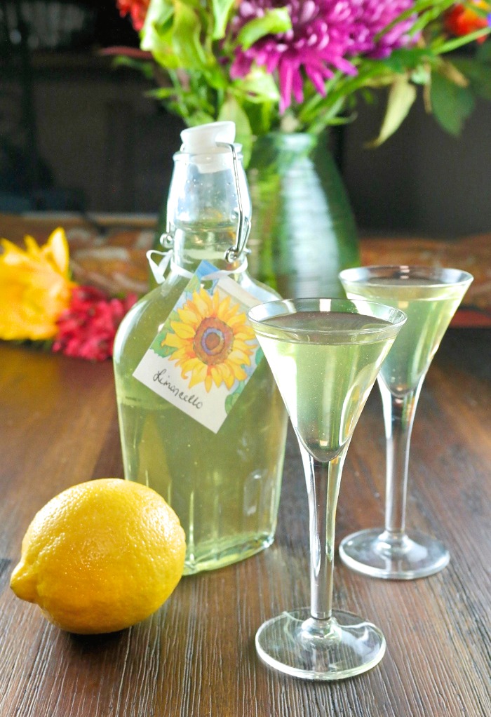 Homemade limoncello recipe in a clear jar and liquor glasses