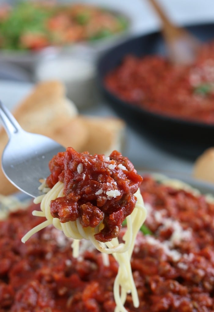 Here we see all the texture and flavor ready to be enjoyed in a close up view of a bite of spaghetti and meat sauce. 