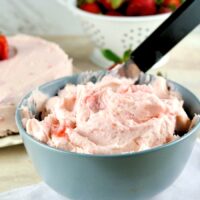 Homemade butter cream frosting with strawberries in a gray-blue bowl