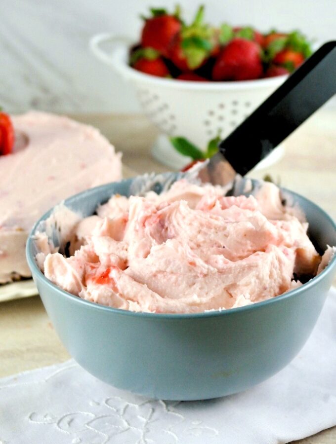 Homemade butter cream frosting with strawberries in a gray-blue bowl