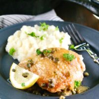 Black plate of low carb chicken piccata and mashed cauliflower