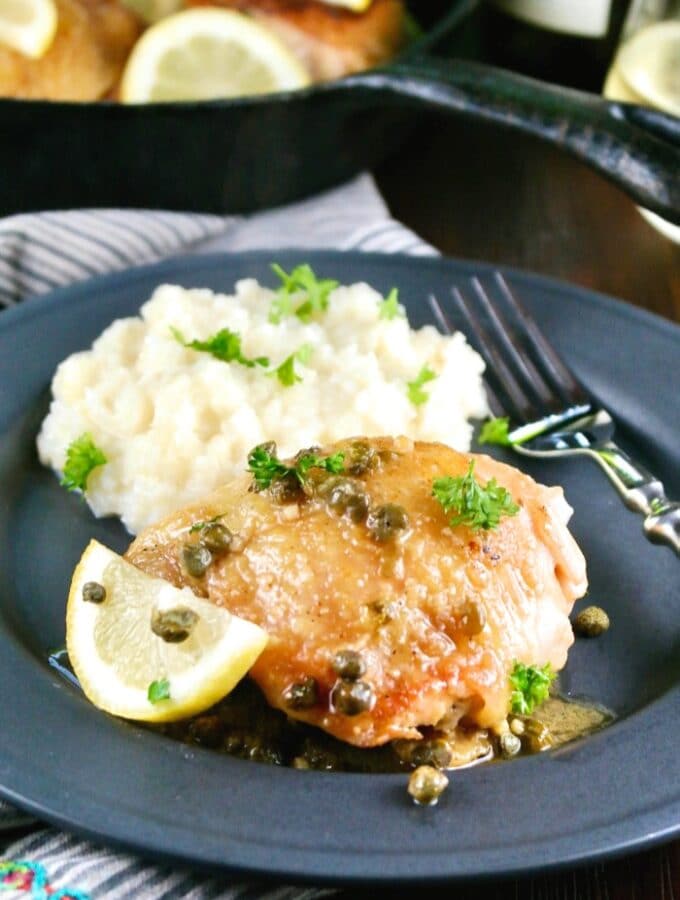 Black plate of low carb chicken piccata and mashed cauliflower