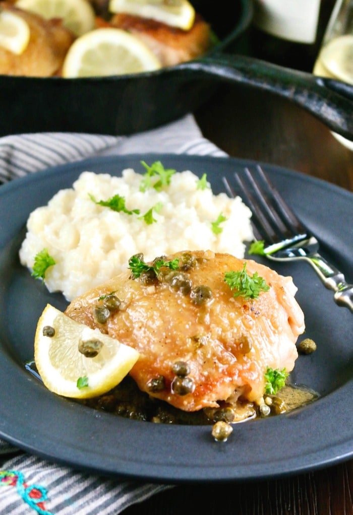 Black plate of low carb chicken piccata and mashed cauliflower