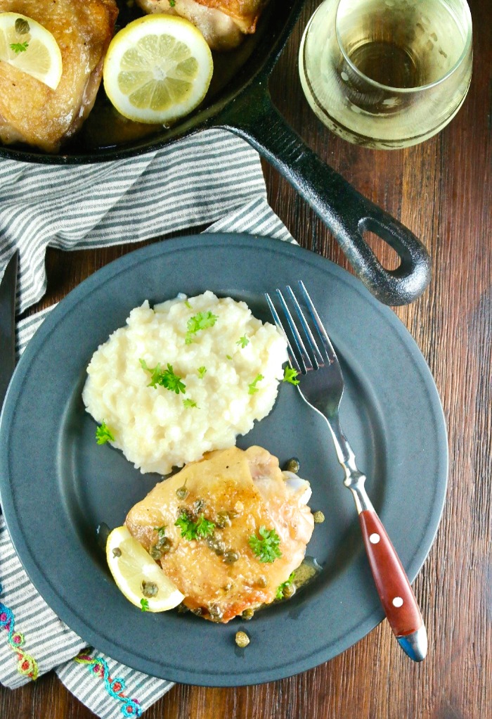 Overhead shot of chicken piccata with a glass of white wine