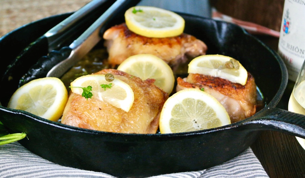 horizontal view of chicken piccata made with thighs in a iron skillet