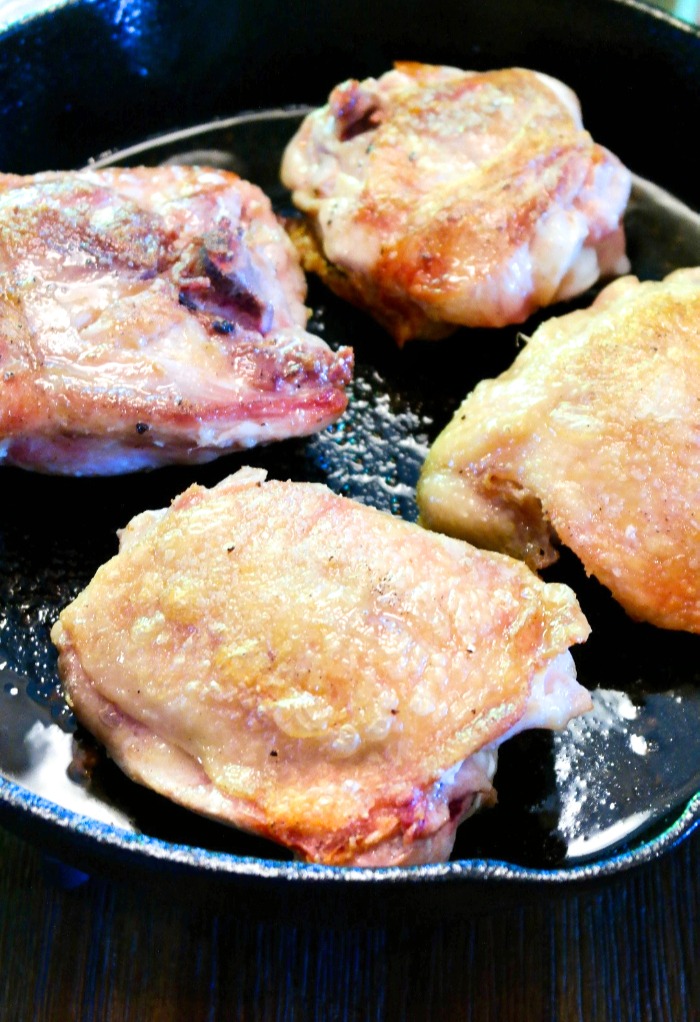 This shows pan frying chicken thighs in a cast iron skillet for an easy chicken piccata recipe