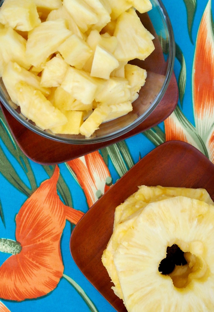 Fresh sliced pineapple and pineapple chunks on brown wooden plates. 