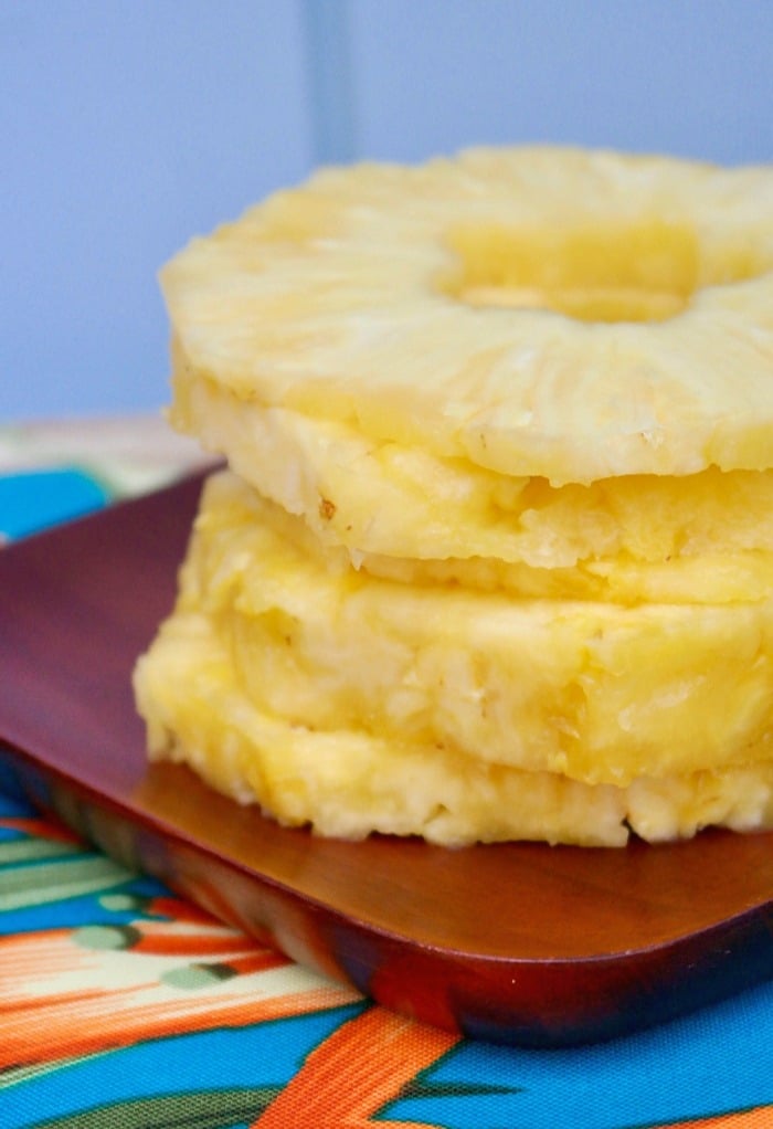 sliced pineapple rings on a brown wood plate