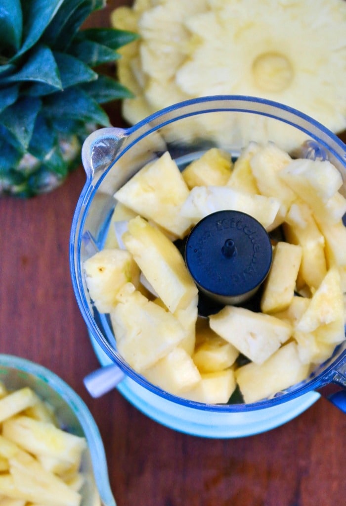 Chunks of pineapple in a teal food processor. 