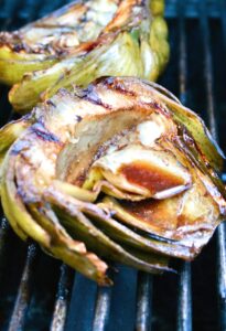 Half artichokes on a grill finishing cooking