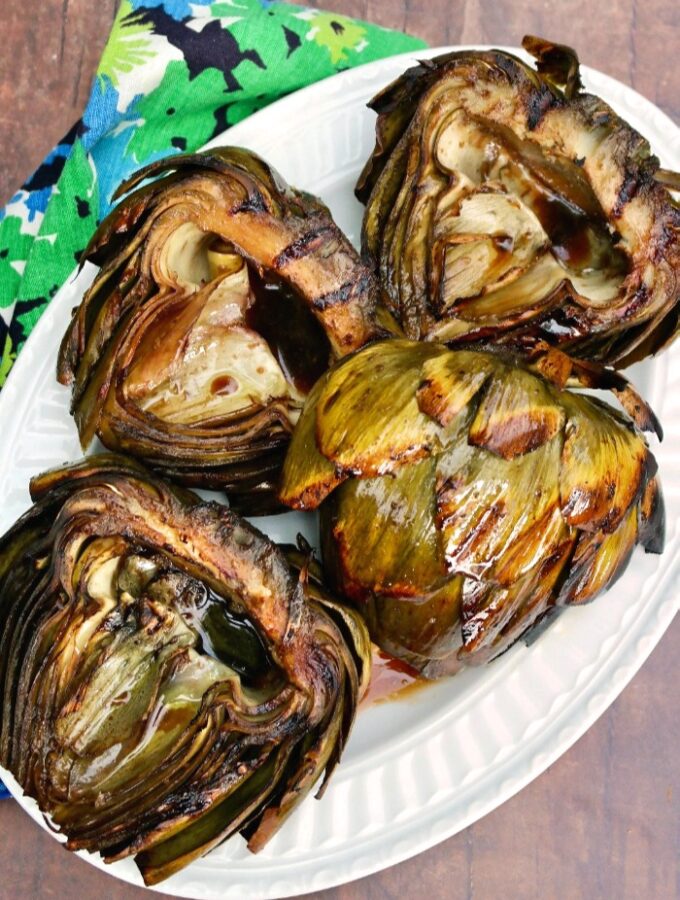 Large globe artichokes grilled and placed on a white platter