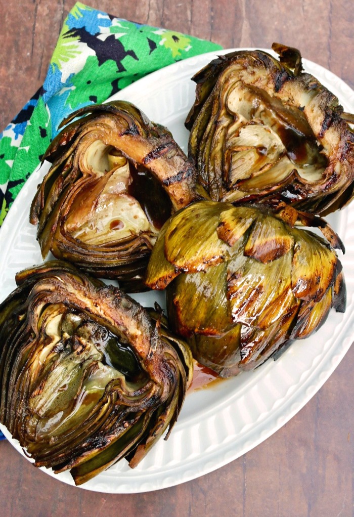 Large globe artichokes grilled and placed on a white platter