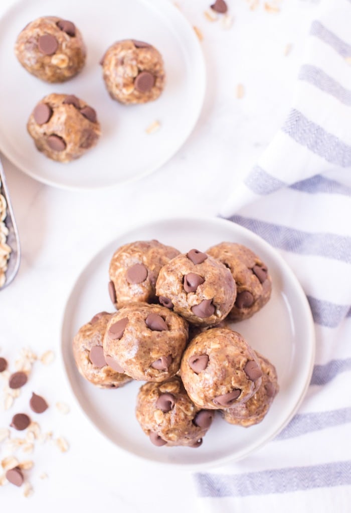 Overhead view of two plates of prepared peanut butter balls on white plates.