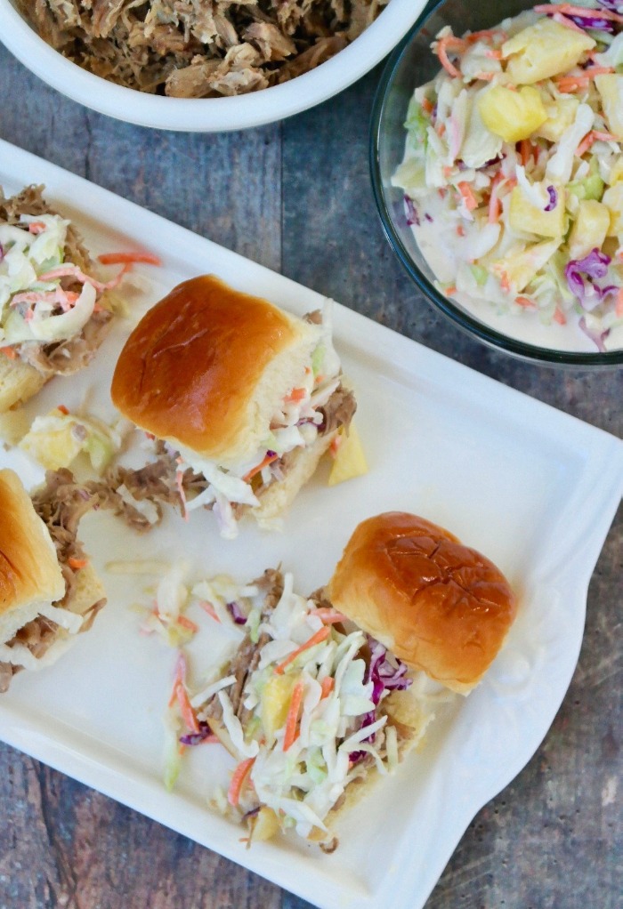 Kalua pork slices topped with coleslaw on a white serving platter.