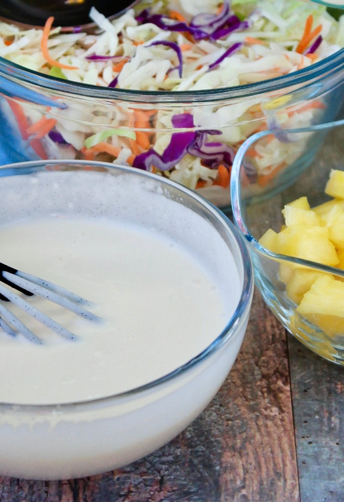 creamy oleslaw dressing in a clear bowl with a whisk