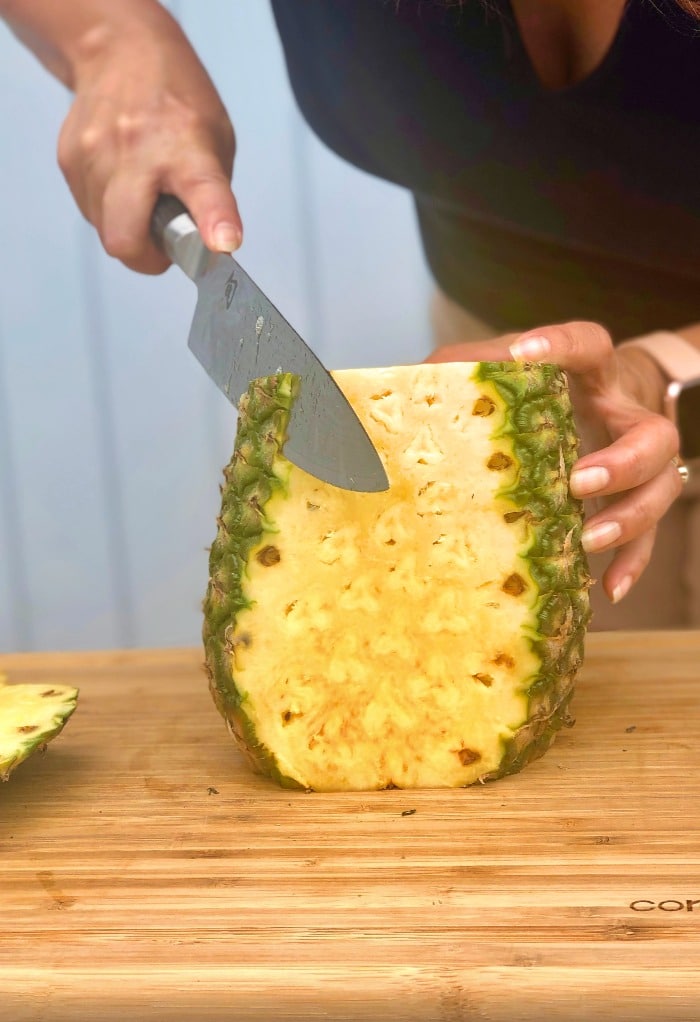 Step by step image how to cut a pineapple slice skin on sides.