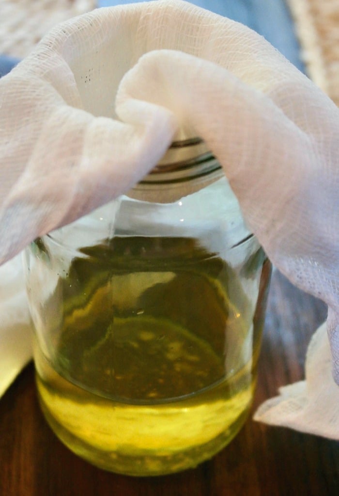 Homemade limoncello with cheesecloth catching the lemon peels to discard