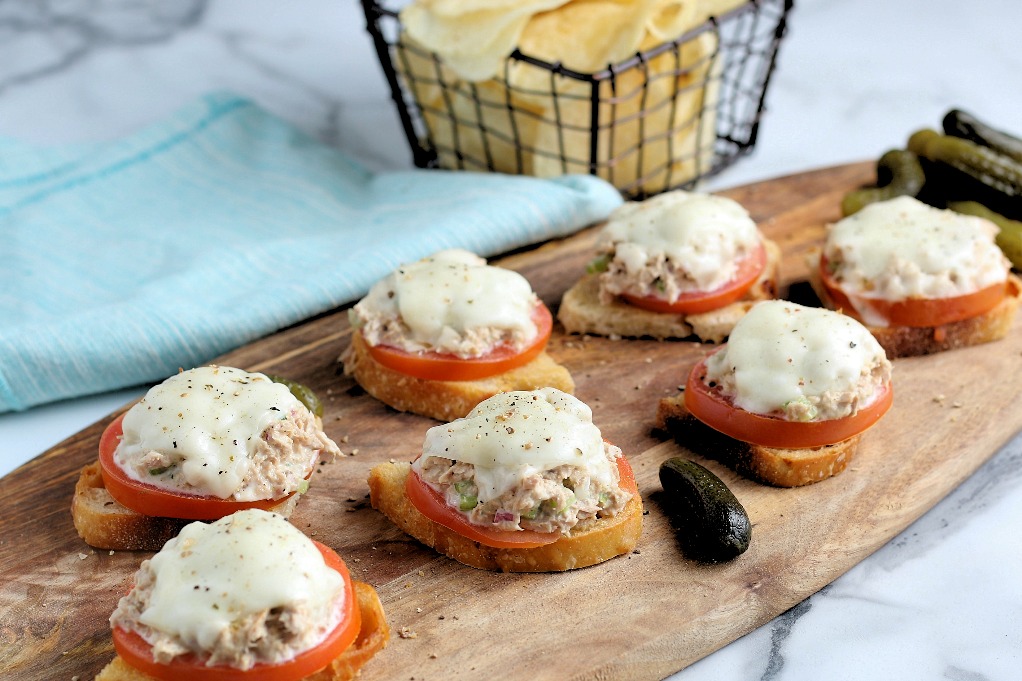 A horizontal view of tuna melt sandwiches on a wooden tray ready to eat.