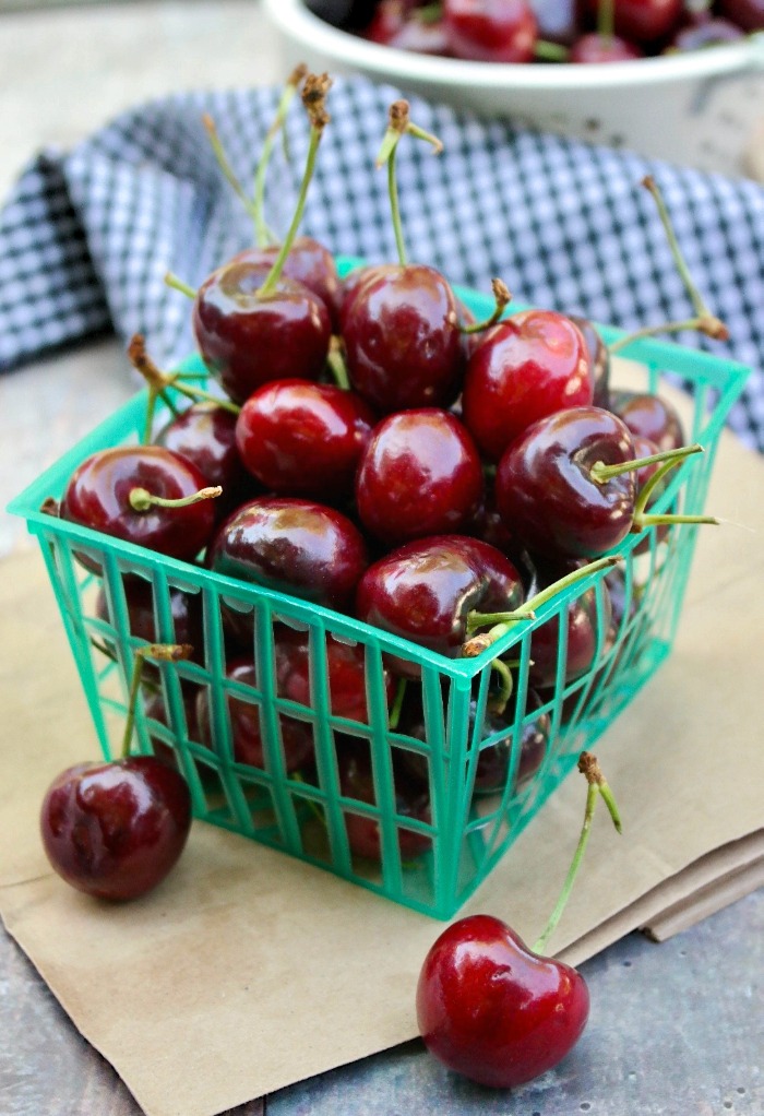 Green plastic basket of fresh cherries for compote.