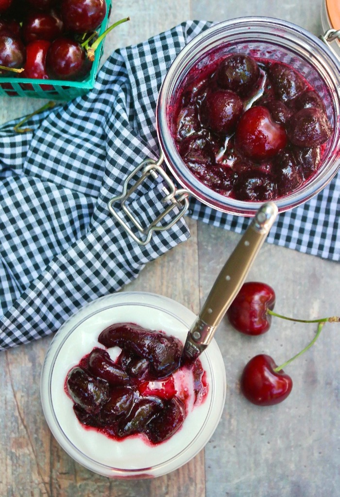 Yogurt in a glass container topped with cherry topping.