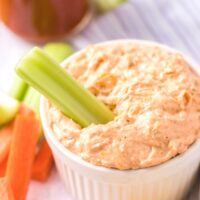 A white bowl with keto buffalo chicken dip with celery.