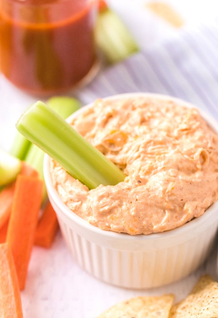 A white bowl with keto buffalo chicken dip with celery.