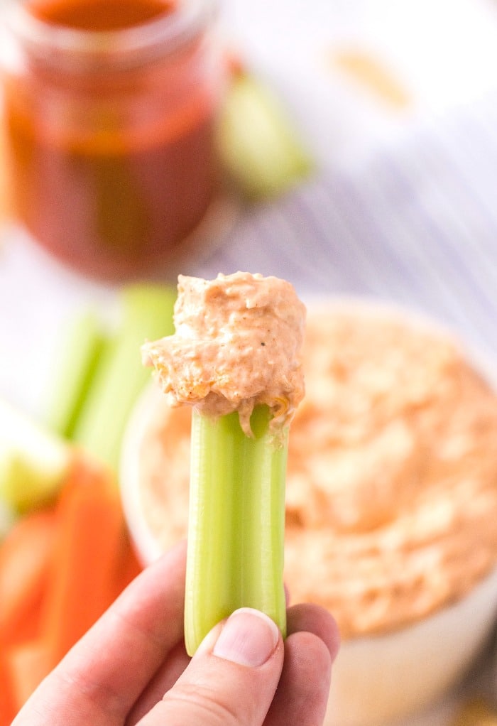 A celery stick with buffalo chicken dip on the end ready to eat. 
