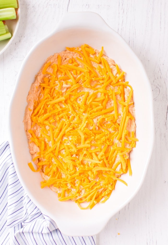Here we add extra cheese to the prepared keto buffalo chicken dip to bake.