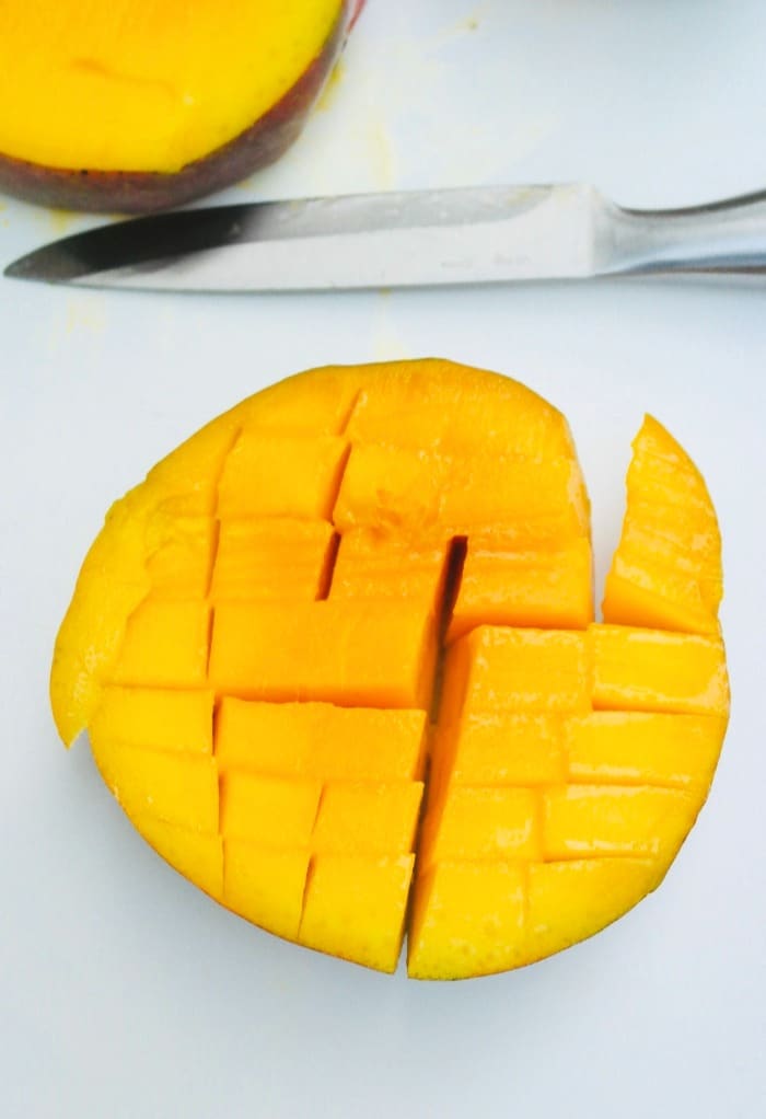 A cut mango with vertical and horizontal slices in a mango.