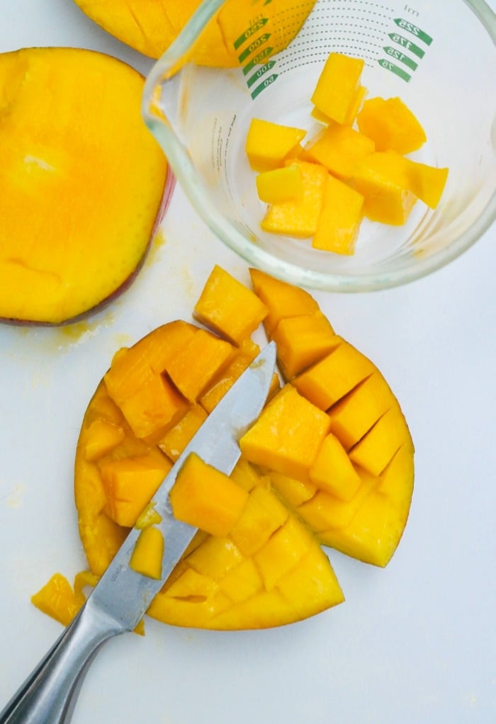 Removing cut mango with a knife.