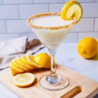 Horizontal view of limoncello martini on a cutting board with sliced lemon