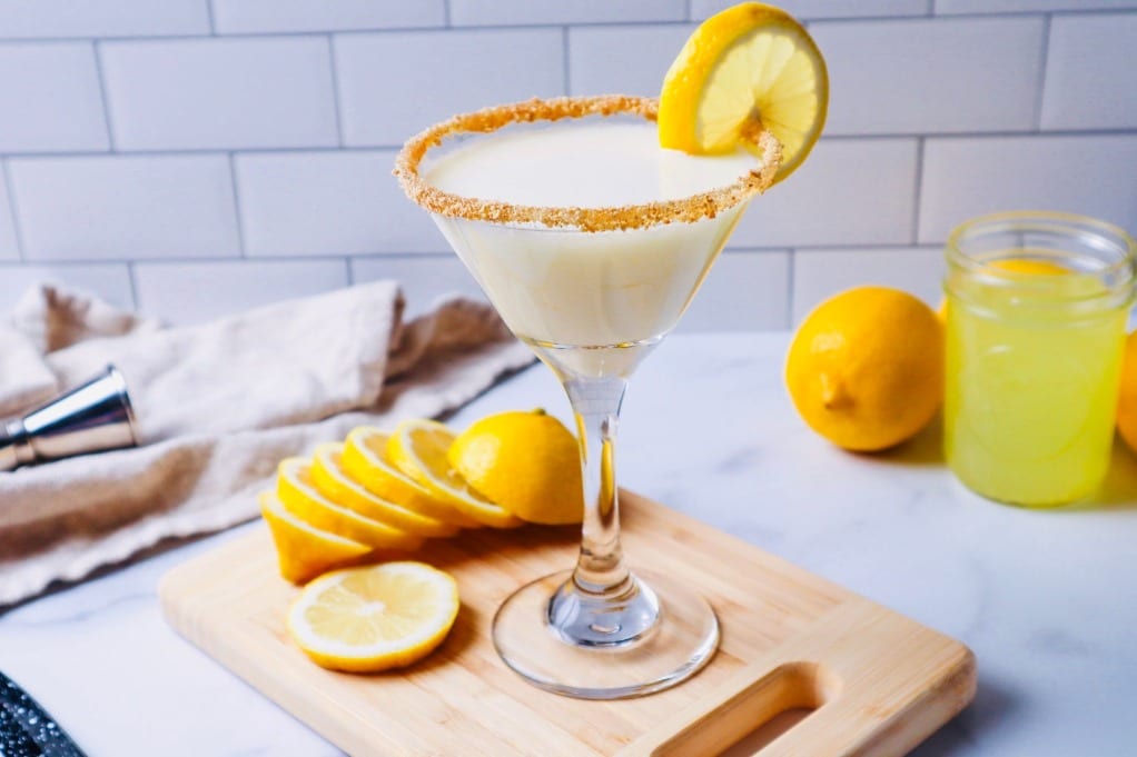 Horizontal view of limoncello martini on a cutting board with sliced lemon