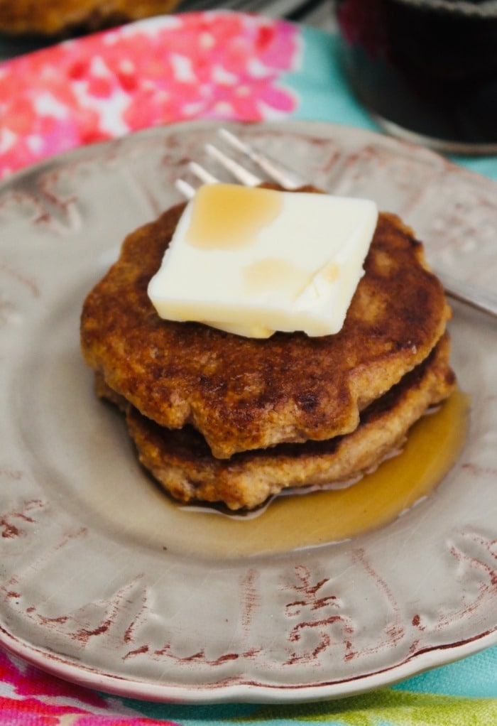 Cinnamon pancakes with butter and syrup on a tan plate. 