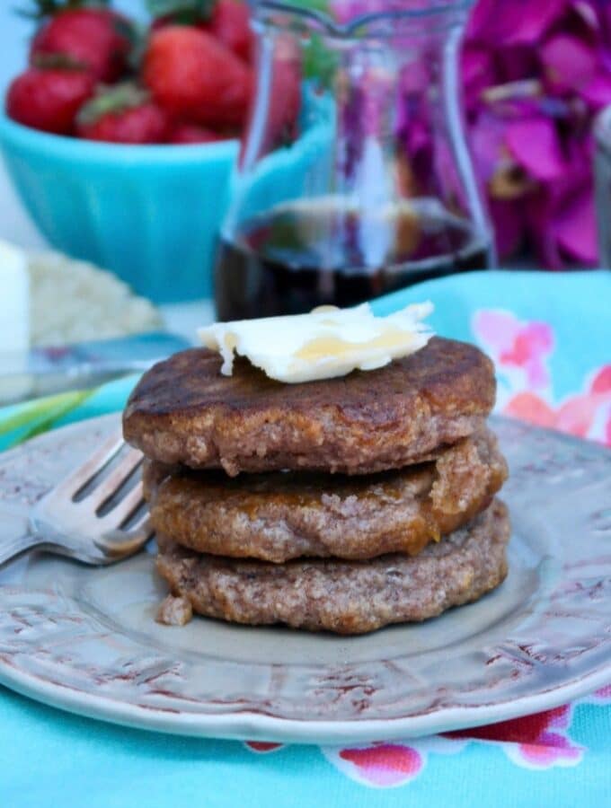 A stack of three low carb pancakes on a tan plate topped with butter.