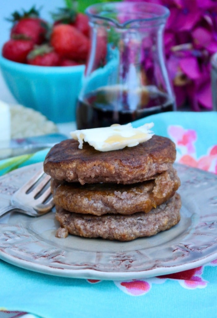 A stack of three low carb pancakes on a tan plate topped with butter.