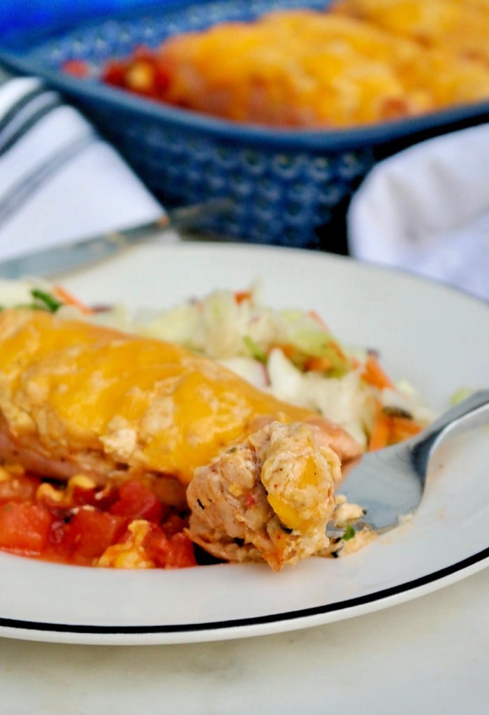 A white plate with cheese stuffed sausage with a fork cutting a piece