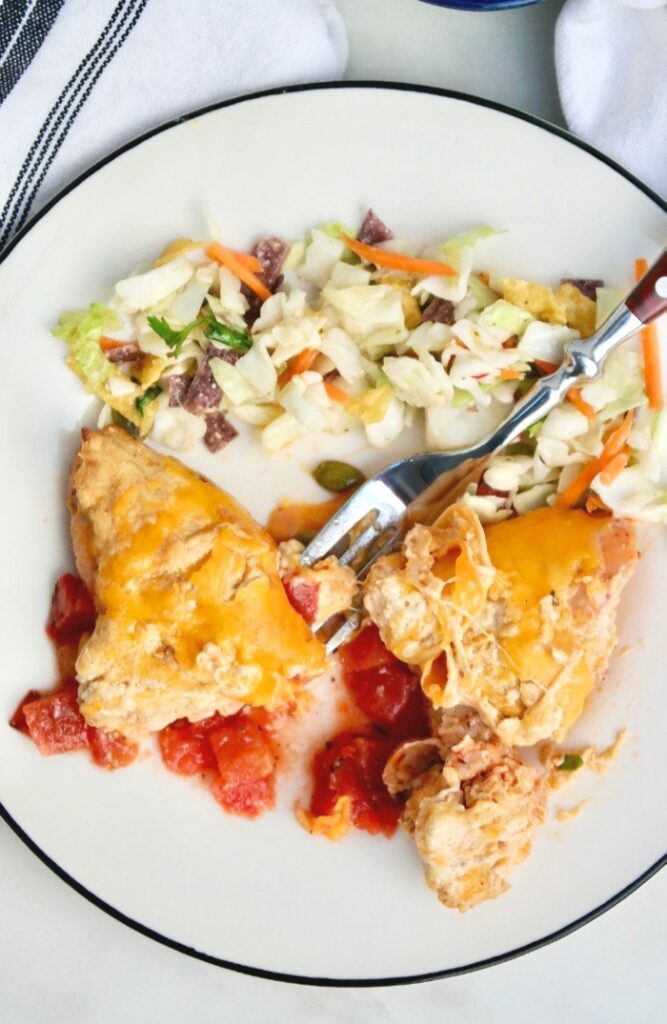 White plate with a black rim of plate of cheese stuffed sausage and salad