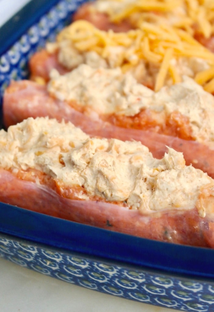 Cheese filled sausage topped with cheddar cheese in a baking dish