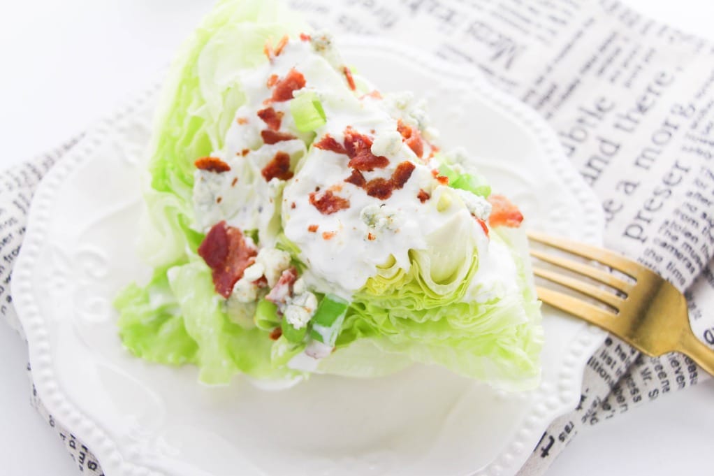 Wedge salad with dressing on a white plate. 