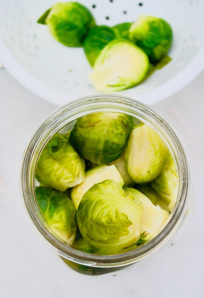 After filling the Mason jar with pickled spices add the Brussels sprouts.
