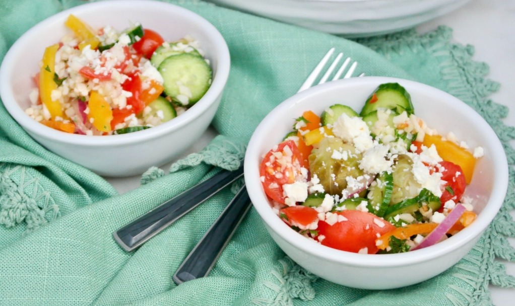 Small salad bowls filled with cauliflower rice salad with Greek dressing ready to be enjoyed. 