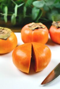 Slice the persimmon in half on a white cutting board.