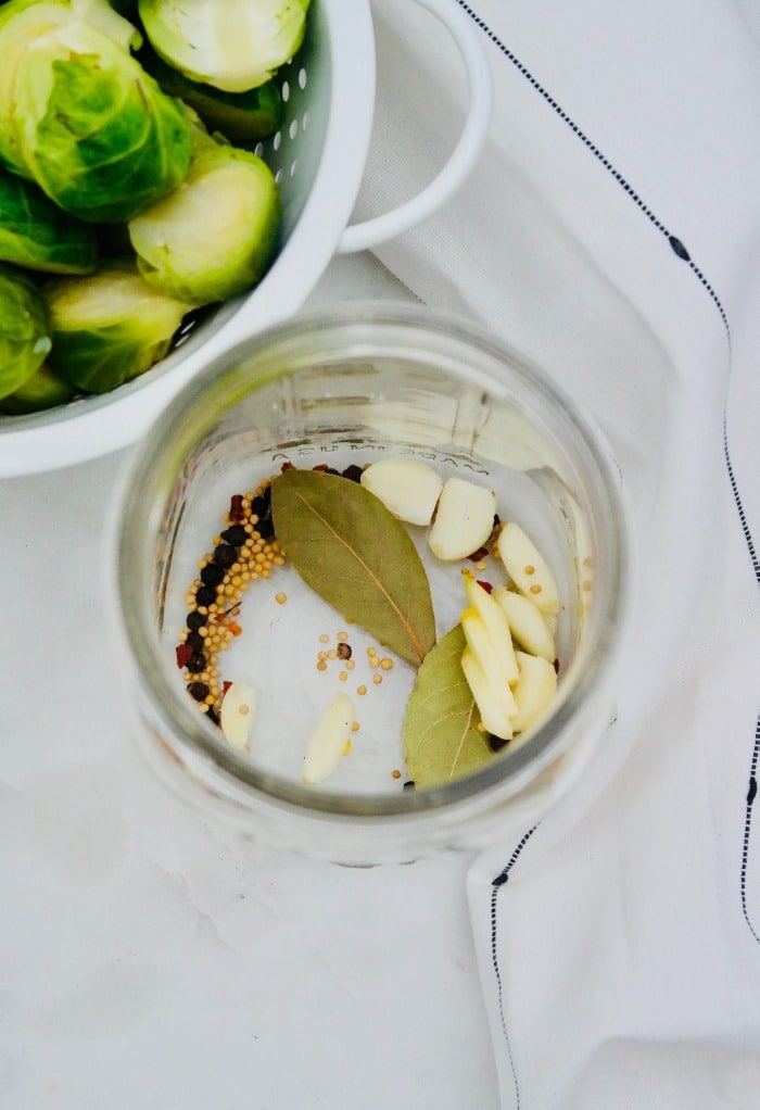 Pickled spices added to a wide mouth clear mason jar. 
