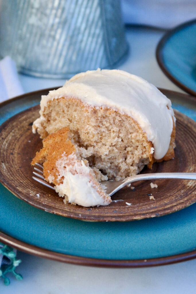 A forkful of spice cake on a tan plate.