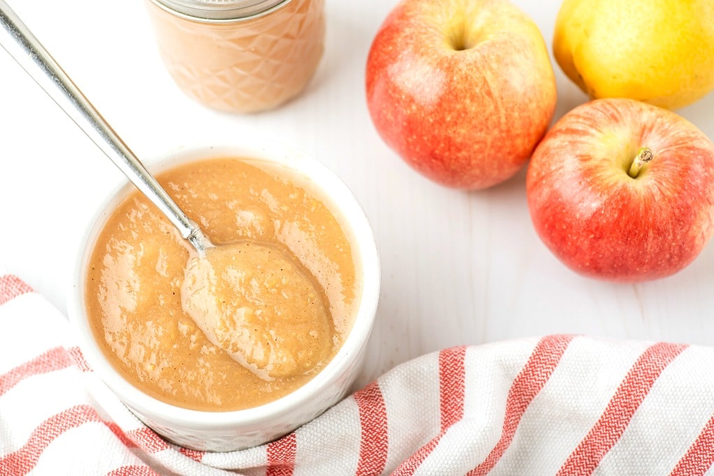 A white bowl with a spoonful of homemade applesauce. 