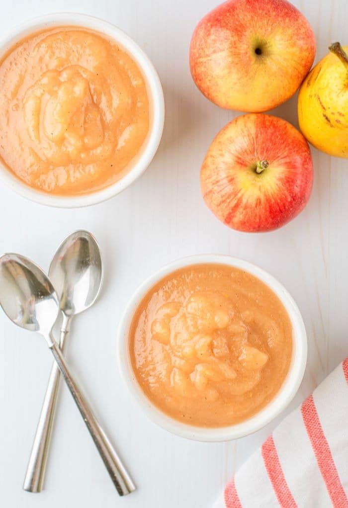 Overhead view of two small white bowls filled with applesauce. 