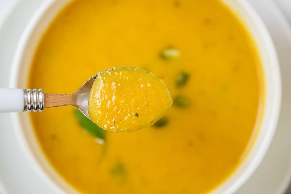 A close up view of a spoonful of butternut squash soup. 
