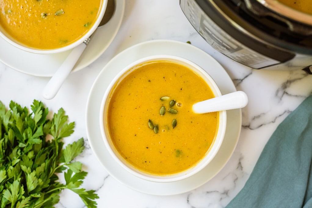 Homemade soup in white bowls with a spoon ready to enjoy 